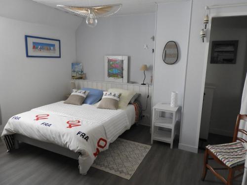 a bedroom with a bed and a chair at les volets bleus in Saint-Guénolé