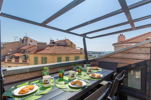 une table avec des assiettes de nourriture sur un balcon dans l'établissement Anzur YourHostHelper, à Cannes