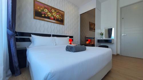 a bedroom with a white bed with a painting on the wall at The Wave Suites Melaka in Melaka
