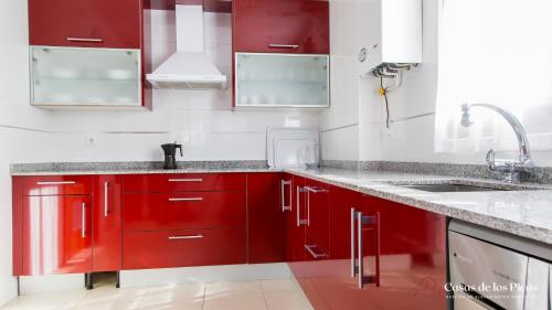 uma cozinha com armários vermelhos e um lavatório em Chalet vacacional Tina Menor - Casas de los Picos em Pesués