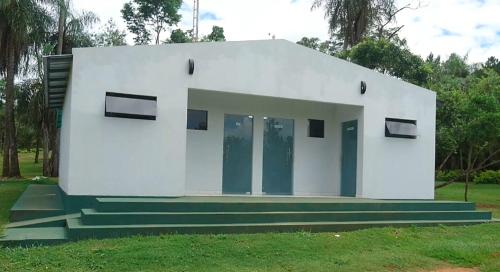 a small white building with stairs in the grass at El Paraje Camping in Piribebuy