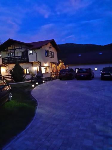 a house with cars parked in a driveway at night at Casa cu Flori in Buşteni