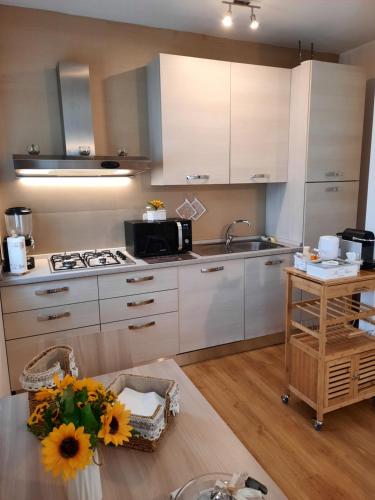 une cuisine avec des placards blancs et une table avec des tournesols dans l'établissement B&B Girasoli, à Ascoli Piceno