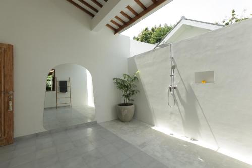 a white bathroom with a shower and a potted plant at The Bingin Beach Villas' Private Villas in Uluwatu