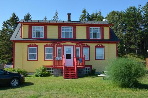 una casa amarilla y roja con una puerta roja en La Maison entre Mer Montagnes, en Cap-Chat