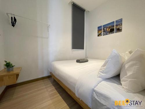 a bedroom with a bed with white sheets and a window at The Wave Suites Melaka in Melaka