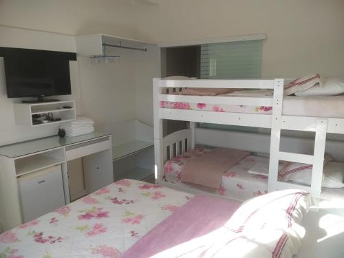 a bedroom with two bunk beds and a desk at Pousada Ares do Sul in Penha