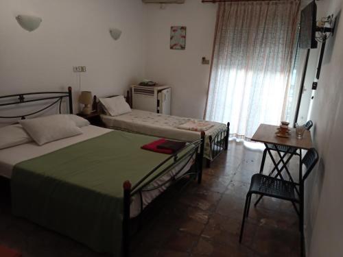 una camera da letto con due letti, un tavolo e una sedia di Nikos Rooms a Loutra Edipsou