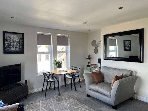 a living room with a table and a couch and a television at Seafront Luxury Apartment in Cleethorpes
