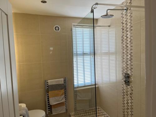 a bathroom with a shower with a toilet and a glass door at Seafront Luxury Apartment in Cleethorpes