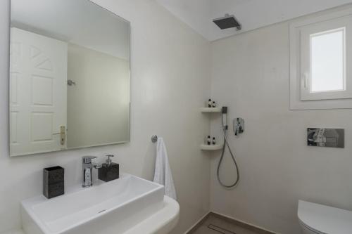 La salle de bains blanche est pourvue d'un lavabo et d'un miroir. dans l'établissement Natalie's apartments, à Adamas