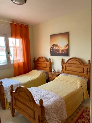 two beds in a bedroom with orange curtains at Apartamento tranquilo en Roses centro cerca de la playa Costa brava in Roses