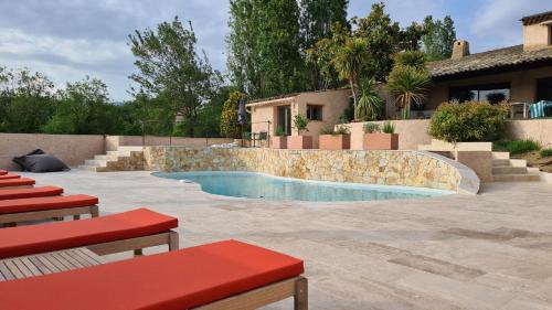a swimming pool in a yard with red benches and a house at Villa Martinus in Saint Paul de Vence