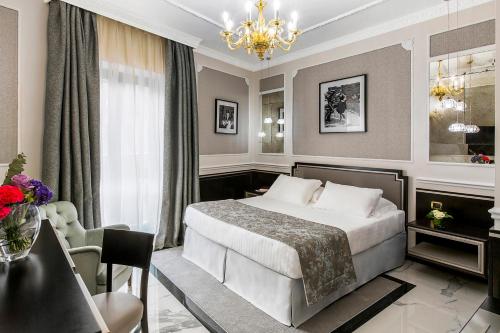 a hotel room with a bed and a chandelier at Baglioni Hotel Regina - The Leading Hotels of the World in Rome