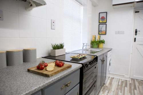 une cuisine équipée d'une planche à découper avec des tomates sur un comptoir dans l'établissement The Flintshire - North Wales - Sleeps Up To 9, à Flint