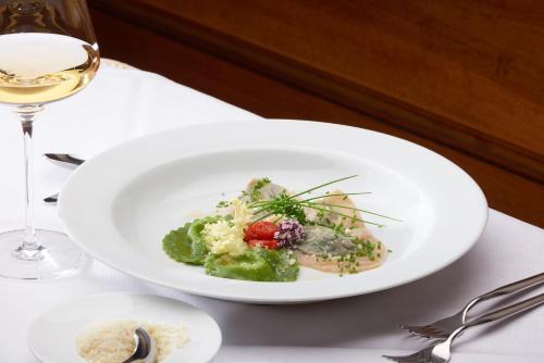 a plate of food on a table with a glass of wine at Parkhotel Post in Chiusa