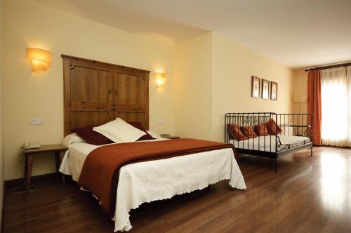 1 dormitorio con 1 cama grande y cabecero de madera en Hotel Pirineos, en Castejón de Sos