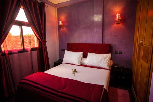 a bedroom with a red and white bed and a window at Toubkal appart hotel in Tahannout