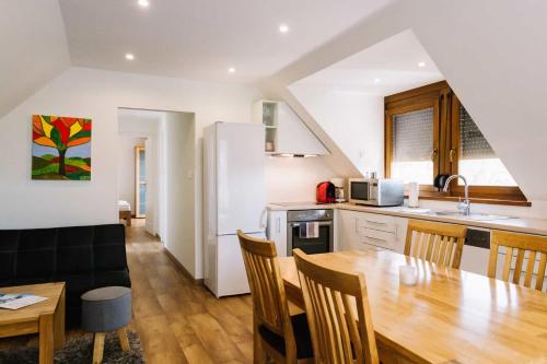 a kitchen and dining room with a wooden table and chairs at Diófa Apartman in Keszthely