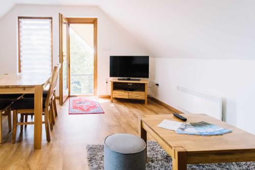 a living room with a dining table and a television at Diófa Apartman in Keszthely