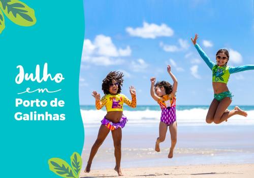 three girls jumping in the air on the beach at Hotel Village Porto De Galinhas in Porto De Galinhas