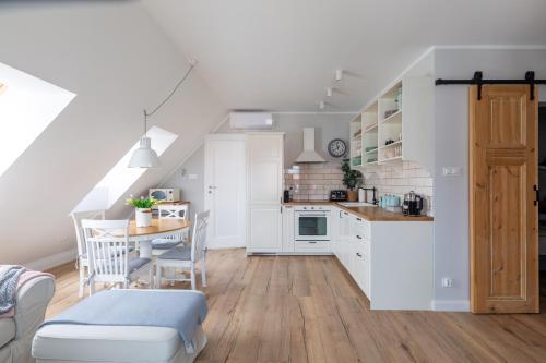 a kitchen and dining room with white cabinets and a table at Apartament Bulvar Starówka in Elblag