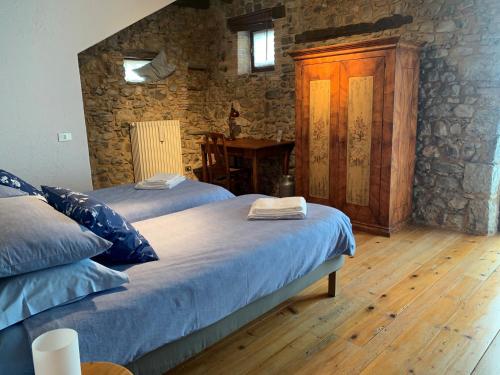 two beds in a room with a stone wall at Al vecchio fienile in Fagagna