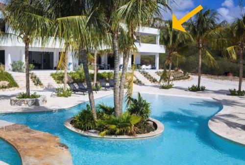 a villa with a swimming pool with a palm tree at Penthouse REEF 5 BEACH GOLF DIVE with Ocean View at Blue Bay Beach in Dorp Sint Michiel