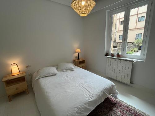 une chambre blanche avec un lit et une fenêtre dans l'établissement Luminoso apartamento en el centro de San Sebastián, à Saint-Sébastien