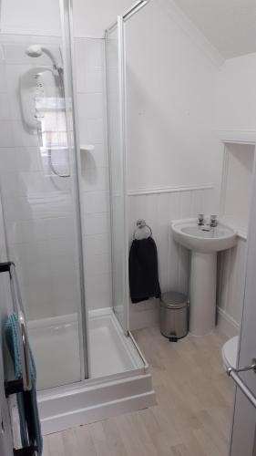 a white bathroom with a shower and a sink at Gynack Villa in Kingussie