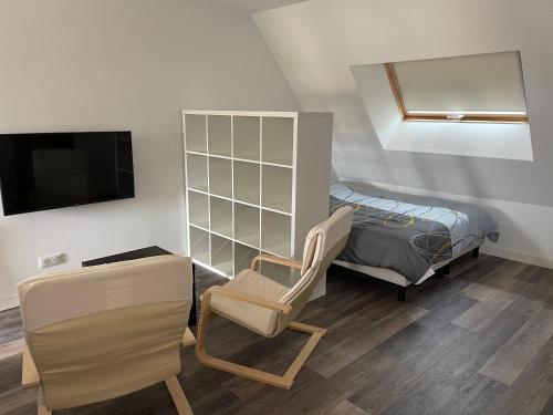 um quarto com uma cama e uma cadeira e uma televisão em Le 33 le Haut em Belfort