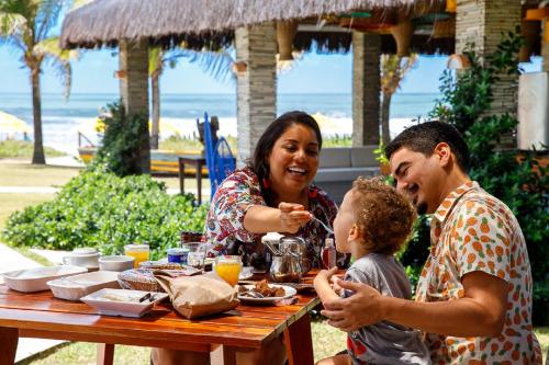 a family sitting at a table eating food at Hotel Village Porto De Galinhas in Porto De Galinhas