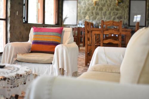 a living room with two white chairs and a colorful pillow at Posada de las Viñas in Tolombón