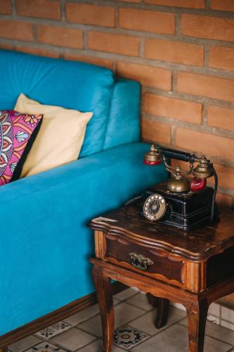 a blue couch with a table with a clock on it at Chalé Refugio da Pedra SP in São Bento do Sapucaí