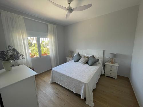 a white bedroom with a bed and a ceiling fan at Casa 1ª linea de playa Benajarafe in Benajarafe