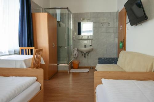 a room with a couch and a bathroom with a sink at Hotel "Wilder Mann" in Linz