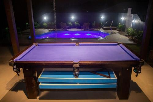 a pool table in front of a swimming pool at night at Casa Green Piccoli - Itajaí/SC in Itajaí