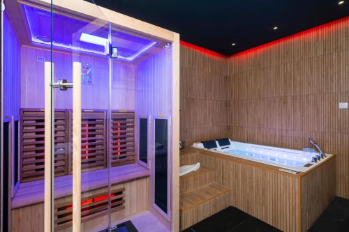 uma casa de banho com uma banheira com iluminação roxa em Art Déco Champagne & Spa em Reims