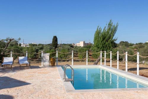 a swimming pool with two chairs next to a fence at Villa Vittoria in Cisternino