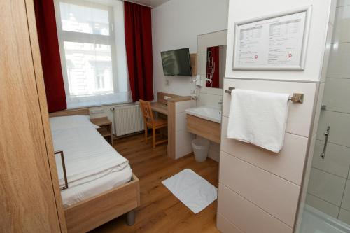 a room with two beds and a desk and a sink at Hotel "Wilder Mann" in Linz