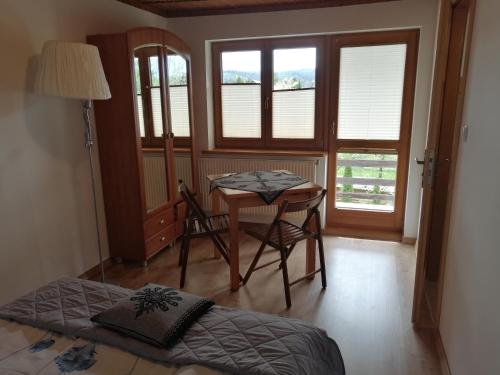 a bedroom with a bed and a table with a chair at Gościniec nad potokiem in Jurgów