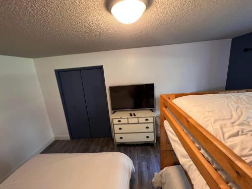 a bedroom with two beds and a flat screen tv at Rustic Girdwood Condo in Girdwood