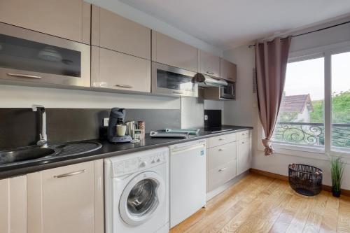 a kitchen with a washer and dryer in it at Studio Moderne & Cosy Proche Paris in Rosny-sous-Bois