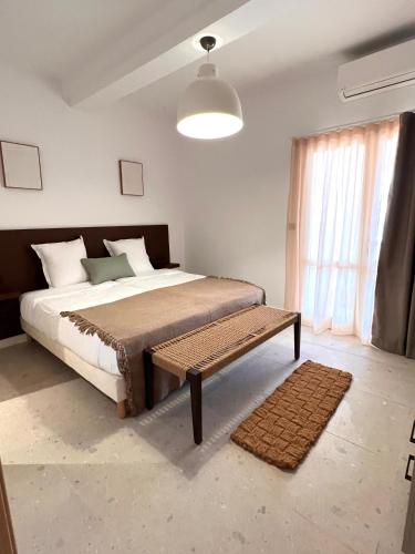 a bedroom with a bed with a bench and a window at Hôtel Serenada in Algajola