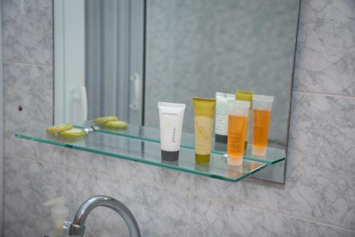 a glass shelf in a bathroom with four cups on it at Daisy's room in Archangelos
