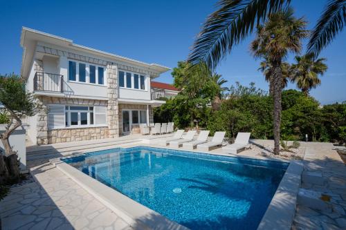 a swimming pool in front of a house at Villa Lucini Dvori in Novalja