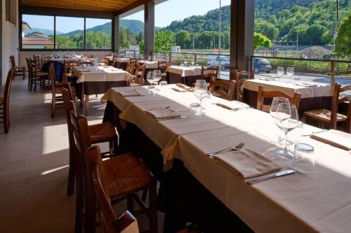 a dining room with tables and chairs and windows at Albergo Shine in Acqualagna