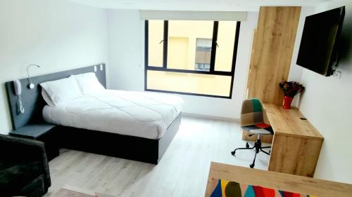 a bedroom with a bed and a desk and a window at Toscana LOFT - Apartasuites in Bogotá