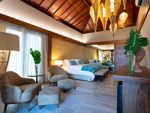 a bedroom with a bed and chairs in a room at Serrambi Resort in Porto De Galinhas