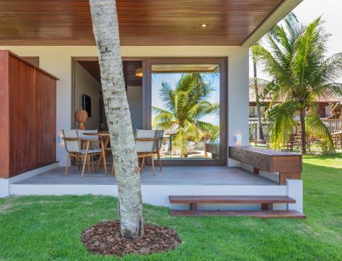 a porch of a house with a table and a tree at Serrambi Resort in Porto De Galinhas